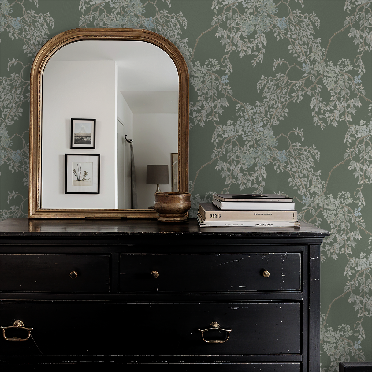 Black dresser with a large mirror against a green floral wallpapered wall.
