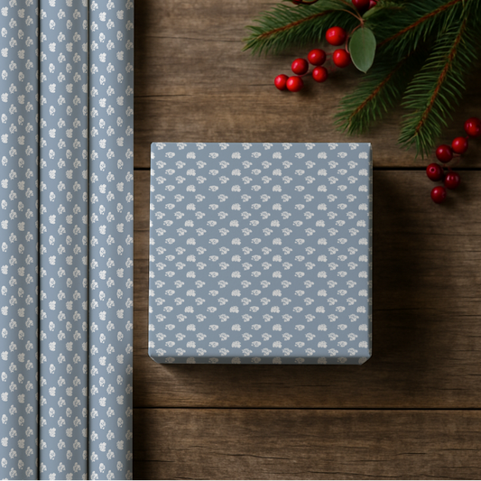 Blue floral-patterned gift box on a wooden surface with wrapped paper and berries.